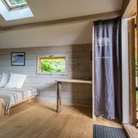Rangement derrière le rideau, un lit simple au rez et une table bureau Cabane de la prairie à louer Vercors